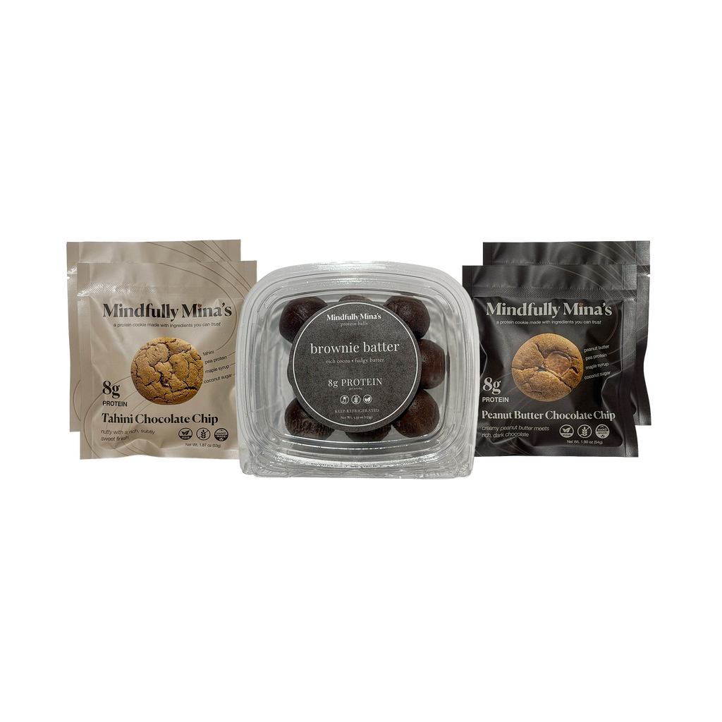 Three Mindfully Mina’s products side by side: a pouch of Tahini Chocolate Chip protein cookies on the left, a clear container of brownie batter protein balls in the center, and a pouch of Peanut Butter Chocolate Chip protein cookies on the right. Each package is labeled “8g protein.”