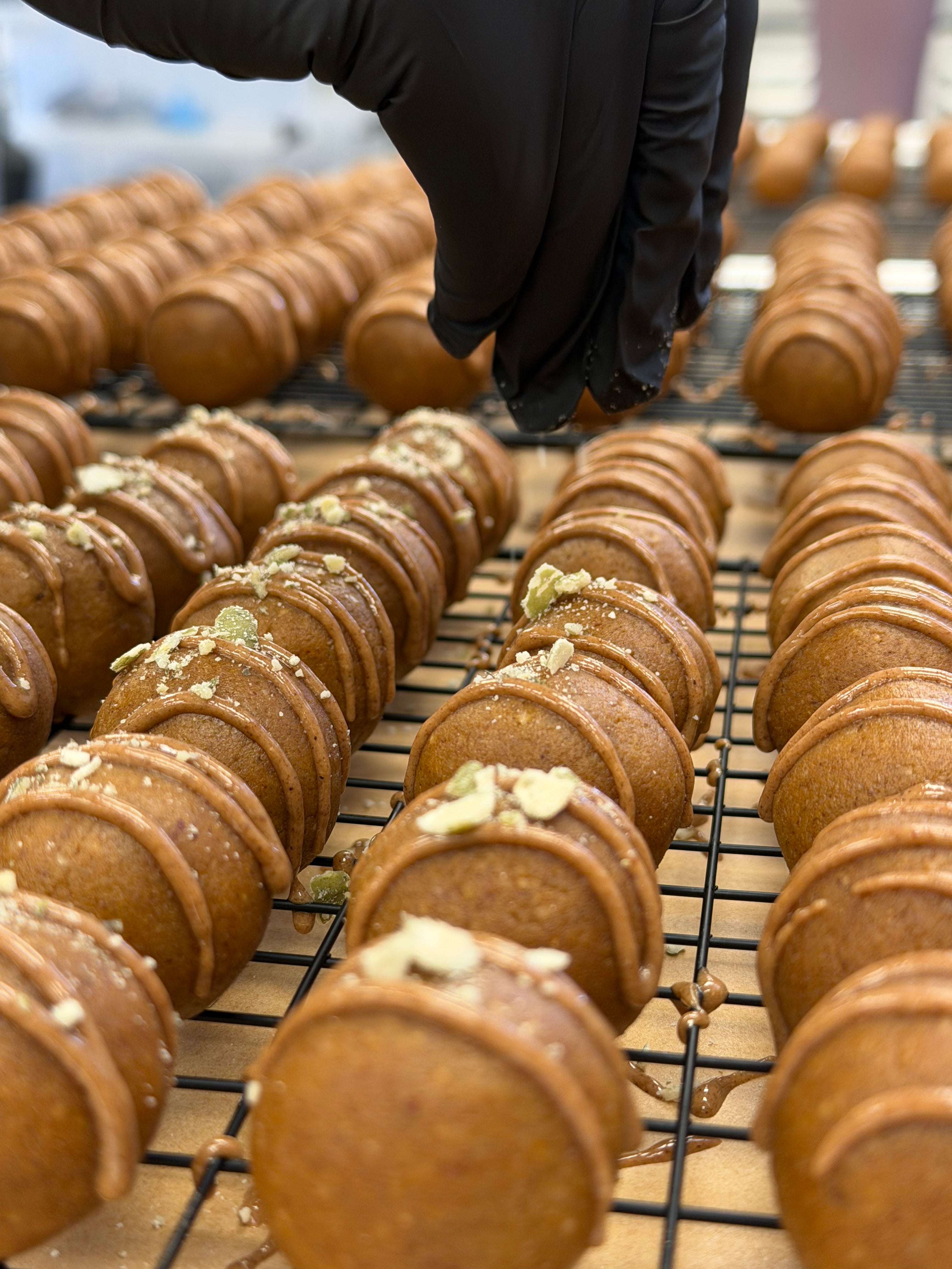 Hand wearing glove sprinkling crushed pumpkin seeds on top of pumpkin pie protein balls 