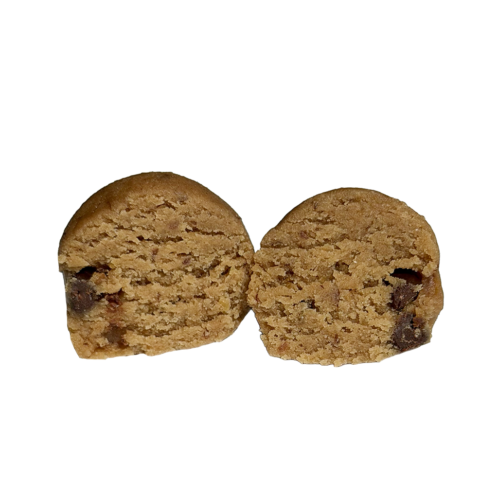 A tahini chocolate chip protein ball cut in half, showing a soft, golden-tan interior with small chocolate chips scattered through it.